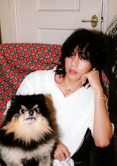 a woman sitting on a couch with a dog in front of her and looking at the camera