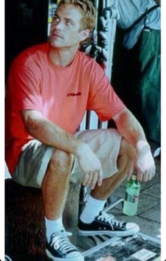 a man sitting on top of a skateboard next to a pile of magazines and bottles