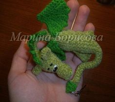 a hand holding a green crocheted stuffed animal