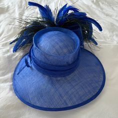 Mad Hatter Kentucky Derby Hat With Feathers And Wide Brim. Blue. String Tightens Head Piece. Kentucky Derby Racetrack Hat. Peacock Like Feathers Blue Wide Brim Fedora For Kentucky Derby, Classic Fitted Blue Hat, Blue Brimmed Cloche Hat For Beach, Blue Brimmed Cloche Hat For The Beach, Blue Adjustable Fedora For Kentucky Derby, Blue Fedora With Short Brim For Parties, Adjustable Blue Cloche Hat With Flat Brim, Blue Fitted Fedora With Flat Brim, Adjustable Blue Fedora For Spring