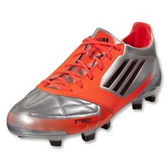 an orange and silver soccer shoe with black stripes on the bottom, and red laces