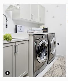 a washer and dryer in a small room with white cupboards on the wall