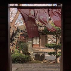 an open door with red flags hanging from it's sides and trees in the background