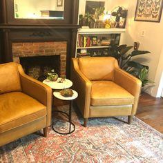 two chairs sitting next to each other on top of a rug in front of a fireplace