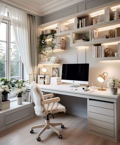 a white desk with a computer on it in front of a window and shelves filled with books