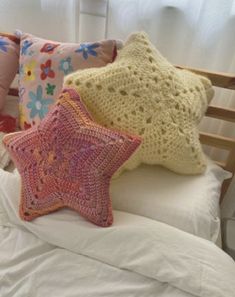 three crocheted stars are on top of a bed with white sheets and pillows