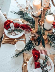 a christmas table setting with candles, plates and napkins