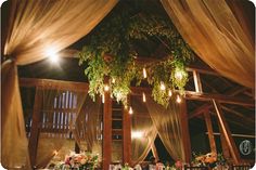 an image of a table setting with flowers and greenery hanging from the ceiling at a wedding reception