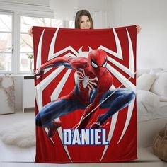 a woman holding up a blanket with the image of spider - man in front of her