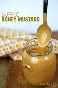 a jar filled with honey sitting on top of a wooden table next to a spoon