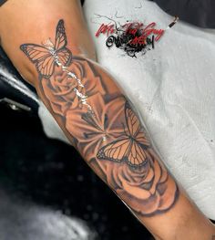 a woman's arm with a butterfly tattoo on it and roses in the background