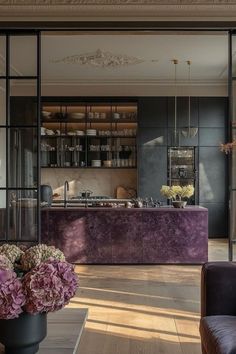 an elegant kitchen with purple furniture and flowers in the vases on the countertop