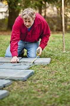 a man kneeling down with a hammer in his hand next to a piece of wood