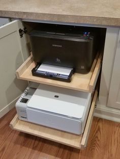 the printer is sitting on top of the shelf in the kitchen cabinet under the counter