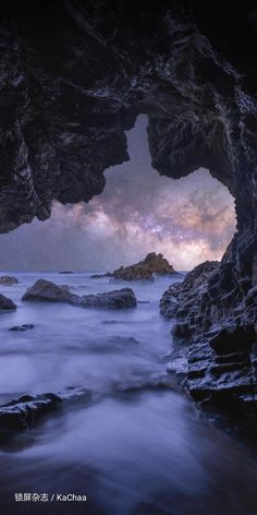 an ocean cave with rocks in the foreground and clouds in the sky above it