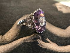 Exquisite in every way, this French Belle Epoque ring centers on 1.03 carat old mine cut diamond, bezel set and seated within an octagonal step cut amethyst. The mounting is like a tiny crown, delicately detailed with lacy openwork and twinkling rose cut diamond details. This beauty sparkles from every angle. Currently a size 5.25. Weight: 8 grams Markings: French dog's head assay mark Measurements: 18.8 x 13.3 mm, sits 11 mm off of the finger Diamonds: estimated 1.03 carat old mine cut, SI2 clarity J-K color, diamond has a closed back. Estimated .20 total carats in rose cut diamonds. https://www.christies.com/lot/lot-a-belle-epoque-amethyst-and-diamond-5269399/?from=salesummary&pos=4&intObjectID=5269399&sid=9614bf2e-38b4-4c3e-b060-d2e25badbe99&page=4 Purple Amethyst Ring With Rose Cut Diamonds, Formal Purple Amethyst Ring With Rose Cut Diamonds, Heirloom Purple Ring With Rose Cut Diamonds, Oval Amethyst Ring With Rose Cut Diamonds, Formal Amethyst Ring With Rose Cut Diamonds, Fine Jewelry Purple Amethyst Ring With Rose Cut Diamonds, Vintage Purple Diamond Ring, Formal Amethyst Rings With Rose Cut Diamonds, Fine Jewelry Amethyst Ring With Rose Cut Diamonds