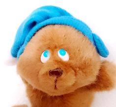 a brown teddy bear with blue eyes and a hat on its head is looking at the camera