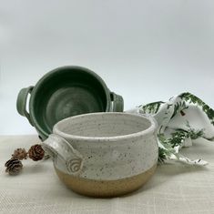 two green and white dishes sitting next to each other on top of a cloth covered table