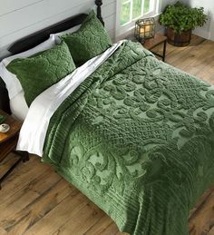 a bed with green bedspread and pillows