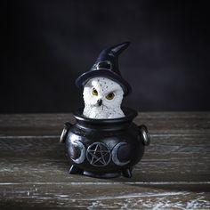 an owl figurine with a witches hat sitting in a black caulder