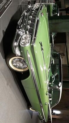 an old green car is on display in a museum