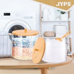 a wooden table topped with containers filled with candy next to a washer and dryer