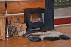 a wood burning stove sitting on top of a hard wood floor next to a basket