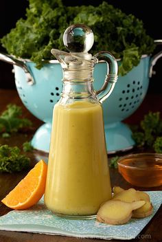 a bottle filled with liquid sitting on top of a table next to oranges and other fruits