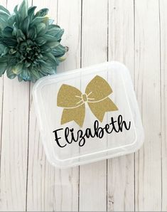 a plastic container with the word elizabeth on it next to a potted green plant