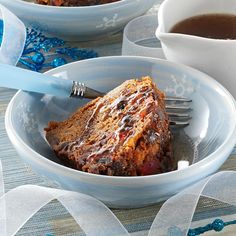 a piece of cake in a bowl next to a cup of coffee on a table