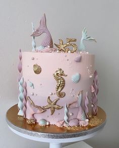 there is a pink cake with gold seahorses on the top and under it