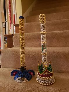 two decorative items are sitting on the carpet next to some stairs, one is made out of beads