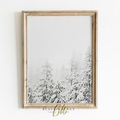 a painting hanging on the wall in front of a white wall with snow covered trees