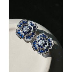 two blue and white diamond earrings on a plate