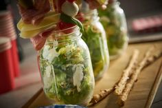 three mason jars filled with salad and cheese sticks