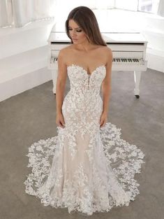 a woman standing in front of a piano wearing a wedding dress with flowers on it