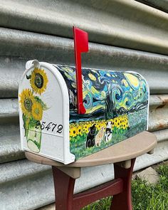 a painted mailbox sitting on top of a wooden bench