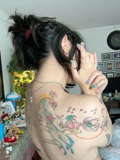 a woman with tattoos on her back is talking on the phone