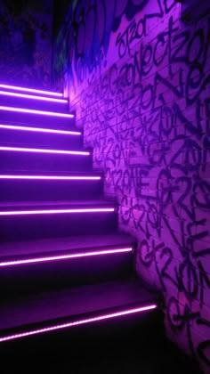 stairs lit up with purple light in front of a wall covered in grafitti