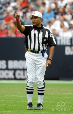 the referee is pointing to his team's play during a football game in front of an audience