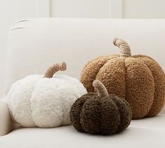 three different colored pumpkins sitting on a white couch