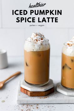 two iced pumpkin spice lattes with whipped cream on top and cinnamon in the bottom