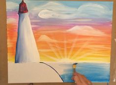 someone is painting a lighthouse at sunset