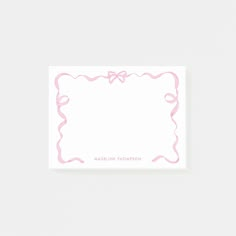 a white card with pink ribbon on it