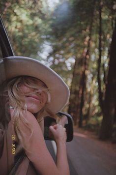 a woman with blonde hair wearing a cowboy hat in the back seat of a car