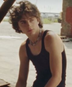 a young man sitting on the ground next to a car