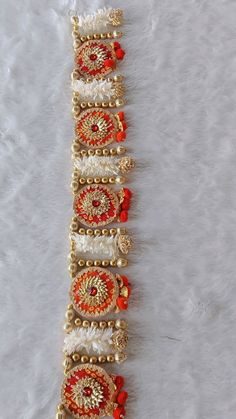 the bracelet is decorated with red and white beads, gold chains, and other bead work