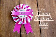 a pink ribbon with the words happy mother's day written on it is sitting on a wooden surface