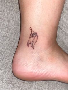 a small tattoo on the ankle of a woman's foot that has a dog with a bone in it