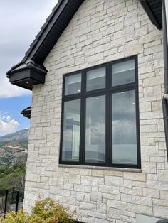 a white brick house with black trim on the windows and side of it, overlooking mountains